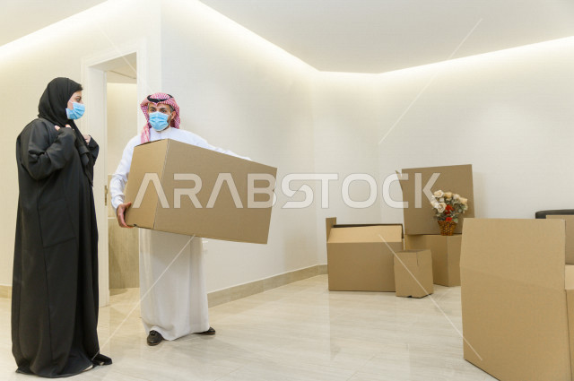 A wonderful atmosphere for a Saudi couple wearing the muzzle inside their new home, moving baggage to a new house, owning a new house, emptying furniture and boxes, arranging and organizing, transporting and delivering