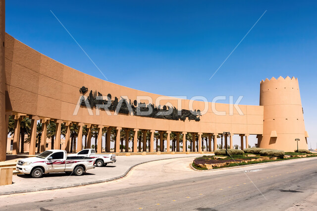 أشجار النخيل حول نصب الفاتحين التاريخي للمؤسس عبد العزيز في مدينة الرياض في النهار، الاهتمام بالتشجير والنباتات الخضراء في الاماكن الاثرية السياحية في المملكة العربية السعودية، معالم الرياض التراثية، فن الهندسة المعمارية والمباني الطينية القديمة