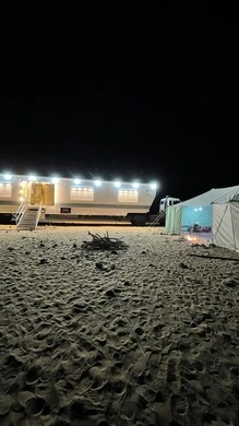 A traditional Arab family tent with a wood stove in the middle of the golden sand, tents in the desert nature, a sleeping caravan that is illuminated at night, camping places and land trips, tourist camps in the Saudi nature.