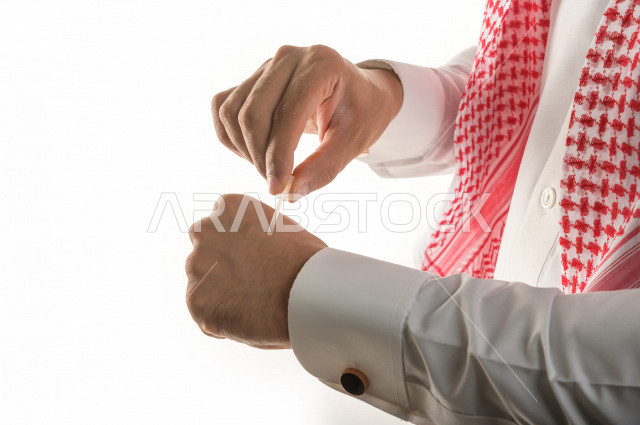 بورتريه لرجل عربي سعودي يختبر تولة من زيت العود العطري الفاخر على الجلد  ، العود العربي السعودي ، استخدام دهن العود في المناسبات الاجتماعية و المناسبات الدينية ،  اصالة العادات و التقاليد في المملكة العربية السعودية ، التطيب و التعطر