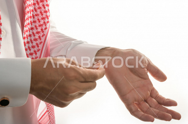 بورتريه لرجل عربي سعودي يختبر تولة من زيت العود العطري الفاخر على الجلد  ، العود العربي السعودي ، استخدام دهن العود في المناسبات الاجتماعية و المناسبات الدينية ،  اصالة العادات و التقاليد في المملكة العربية السعودية ، التطيب و التعطر
