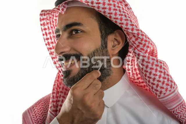 بورتريه لرجل عربي سعودي يختبر تولة من زيت العود العطري الفاخر على الجلد  ، العود العربي السعودي ، استخدام دهن العود في المناسبات الاجتماعية و المناسبات الدينية ،  اصالة العادات و التقاليد في المملكة العربية السعودية ، التطيب و التعطر
