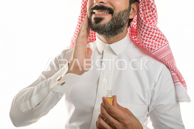 Portrait of a Saudi Arab man testing a tola of the luxurious oud aromatic oil on the skin, the Saudi Arabian oud, the use of oud oil in social and religious occasions, the originality of customs and traditions in the Kingdom of Saudi Arabia, perfume and p