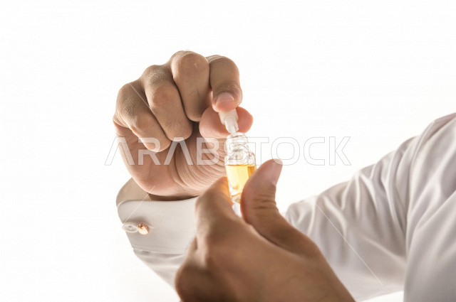 بورتريه لرجل عربي سعودي يختبر تولة من زيت العود العطري الفاخر على الجلد  ، العود العربي السعودي ، استخدام دهن العود في المناسبات الاجتماعية و المناسبات الدينية ،  اصالة العادات و التقاليد في المملكة العربية السعودية ، التطيب و التعطر