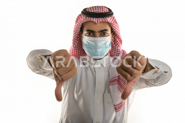 بورتريه لشاب سعودي يرتدي الكمامة ، يرفع يده ليتجنب المصافحة واقتراب الاخرين منه ، تجنب انتشار العدوى ، الحفاظ على المسافات ، خلفية بيضاء