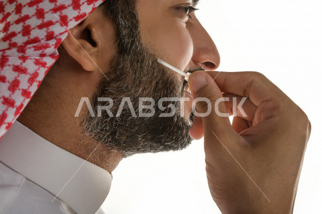 بورتريه لرجل عربي سعودي يختبر تولة من زيت العود العطري الفاخر على الجلد  ، العود العربي السعودي ، استخدام دهن العود في المناسبات الاجتماعية و المناسبات الدينية ،  اصالة العادات و التقاليد في المملكة العربية السعودية ، التطيب و التعطر