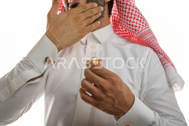 بورتريه لرجل عربي سعودي يختبر تولة من زيت العود العطري الفاخر على الجلد  ، العود العربي السعودي ، استخدام دهن العود في المناسبات الاجتماعية و المناسبات الدينية ،  اصالة العادات و التقاليد في المملكة العربية السعودية ، التطيب و التعطر