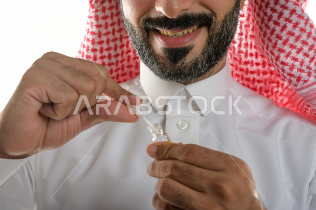 بورتريه لرجل عربي سعودي يختبر تولة من زيت العود العطري الفاخر على الجلد  ، العود العربي السعودي ، استخدام دهن العود في المناسبات الاجتماعية و المناسبات الدينية ،  اصالة العادات و التقاليد في المملكة العربية السعودية ، التطيب و التعطر