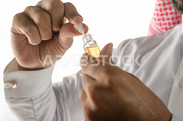 بورتريه لرجل عربي سعودي يختبر تولة من زيت العود العطري الفاخر على الجلد  ، العود العربي السعودي ، استخدام دهن العود في المناسبات الاجتماعية و المناسبات الدينية ،  اصالة العادات و التقاليد في المملكة العربية السعودية ، التطيب و التعطر