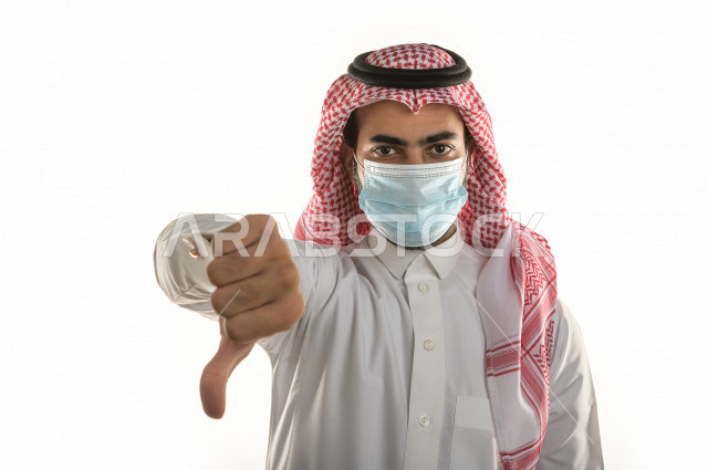 بورتريه لشاب سعودي يرتدي الكمامة ، يرفع يده ليتجنب المصافحة واقتراب الاخرين منه ، تجنب انتشار العدوى ، الحفاظ على المسافات ، خلفية بيضاء