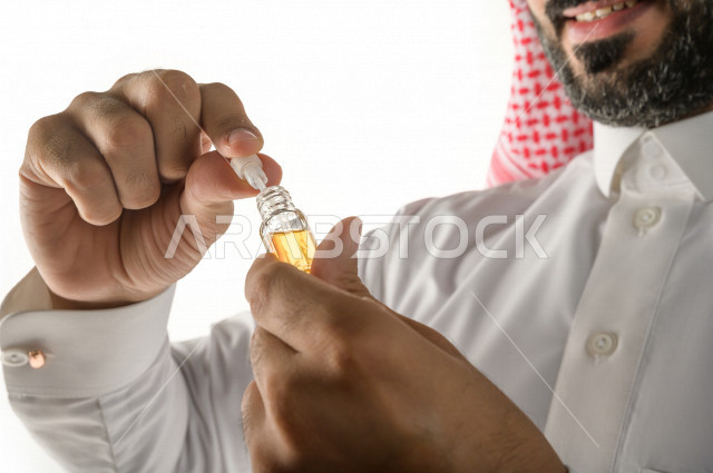بورتريه لرجل عربي سعودي يختبر تولة من زيت العود العطري الفاخر على الجلد  ، العود العربي السعودي ، استخدام دهن العود في المناسبات الاجتماعية و المناسبات الدينية ،  اصالة العادات و التقاليد في المملكة العربية السعودية ، التطيب و التعطر