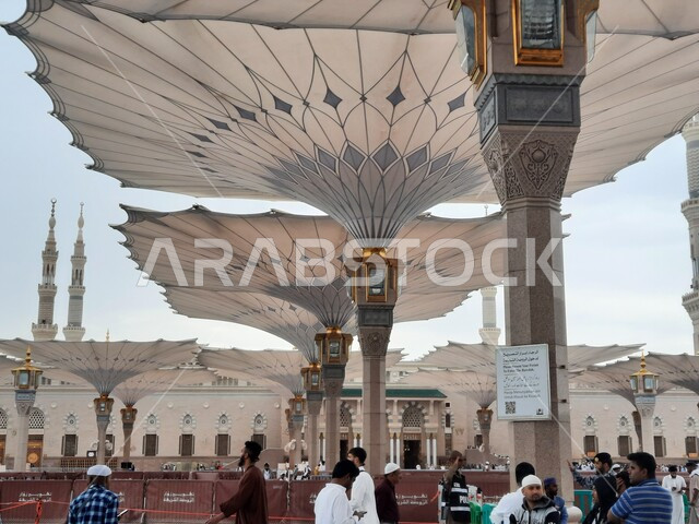 المعالم الاسلامية المقدسة, قدوم الناس من شتى أنحاء العالم لأداء العبادات والفرائض, تجمع المسلمين في الساحة الخارجية للمسجد النبوي الشريف في المدينة المنورة, أماكن دينية وأجواء روحانية, المآذن والقبب والمظلات الالكترونية الحديثة