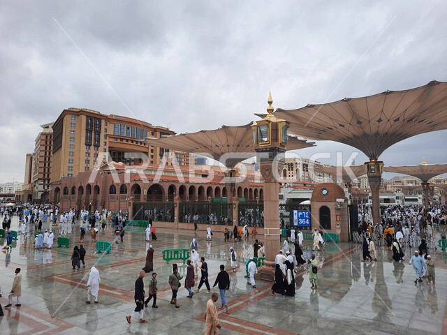 منظر السماء المليئة بالغيوم البيضاء, تجمع المسلمين في الساحة الخارجية للمسجد النبوي الشريف في المدينة المنورة, أماكن أداء العبادات والفرائض, العبادة والتقرب إلى الله تعالى, معالم اسلامية مشهورة في السعودية, المظلات الالكترونية الحديثة في المجمع الخارجي