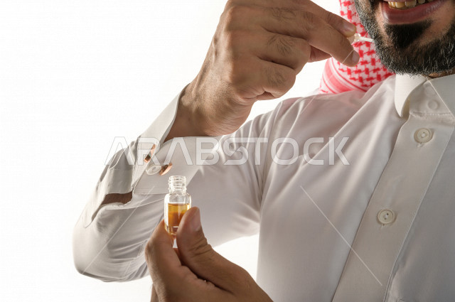 بورتريه لرجل عربي سعودي يختبر تولة من زيت العود العطري الفاخر على الجلد  ، العود العربي السعودي ، استخدام دهن العود في المناسبات الاجتماعية و المناسبات الدينية ،  اصالة العادات و التقاليد في المملكة العربية السعودية ، التطيب و التعطر