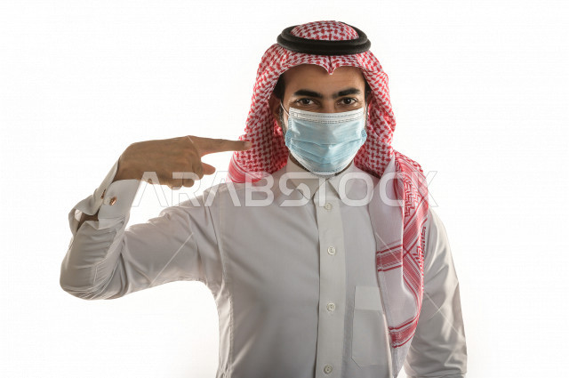 Portrait of a Saudi youth wearing the muzzle, following safety procedures, applying the muzzle correctly, avoiding the spread of infection, white background