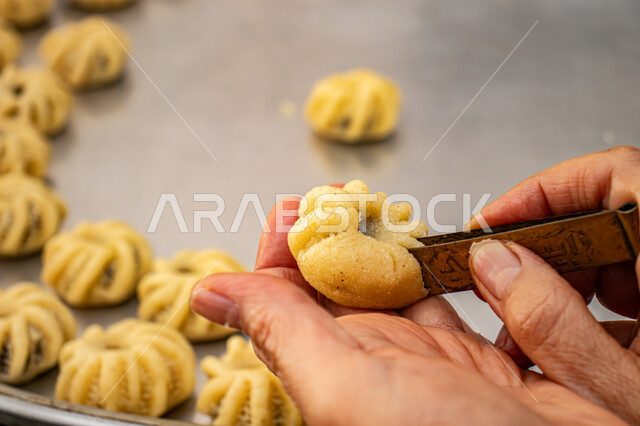  الاستعداد لاستقبال الأعياد والمناسبات الإسلامية السعيدة، قطع معمول العيد الشهية، كرم الضيافة وحسن الاستقبال في السعودية, منتجات محلية وطنية، حلى سعودي بالعجوة والمكسرات، صورة مقربة ليد إمرأة تقوم بتشكيل قرص المعمول، طريقة إعداد وتحضير الحلويات الشهية