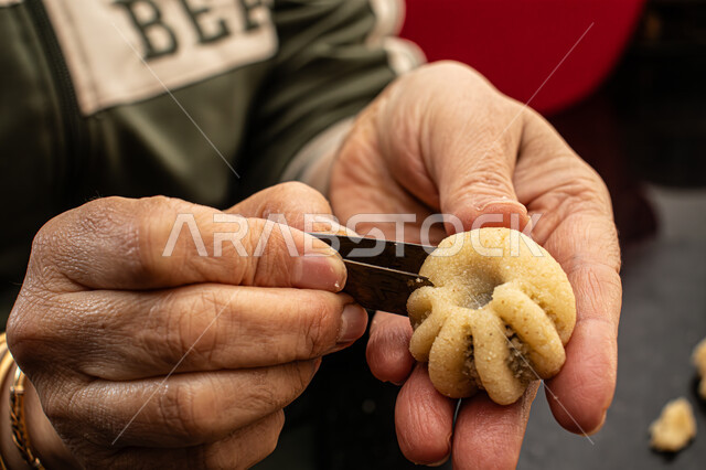 طريقة إعداد وتحضير الحلويات الشهية، الاستعداد لاستقبال الأعياد والمناسبات الإسلامية السعيدة، قطع معمول العيد الشهية، كرم الضيافة وحسن الاستقبال في السعودية, منتجات محلية وطنية، حلى سعودي بالعجوة والمكسرات، صورة مقربة ليد إمرأة تقوم بتشكيل قرص المعمول