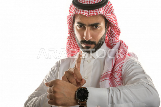 بورتريه لرجل سعودي خليجي  سعيد بإيماءات الوجه المختلفة  ، تعابير وجه و يدين مختلفة  ، يرتدي ساعة يد فاخرة  ، يشير اصبعه الى الساعة ،خلفية بيضاء