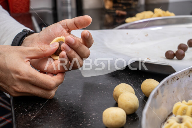  الاستعداد لاستقبال الأعياد والمناسبات الإسلامية السعيدة، قطع معمول العيد الشهية، كرم الضيافة وحسن الاستقبال في السعودية, منتجات محلية وطنية، حلى سعودي بالعجوة والمكسرات، صورة مقربة ليد إمرأة تقوم بتشكيل قرص المعمول، طريقة إعداد وتحضير الحلويات الشهية