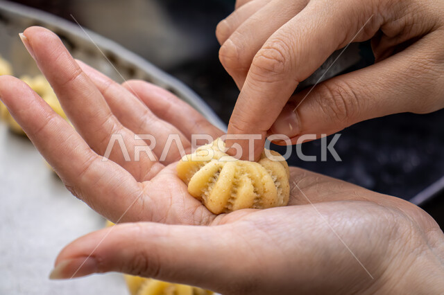  الاستعداد لاستقبال الأعياد والمناسبات الإسلامية السعيدة، قطع معمول العيد الشهية، كرم الضيافة وحسن الاستقبال في السعودية, منتجات محلية وطنية، حلى سعودي بالعجوة والمكسرات، صورة مقربة ليد إمرأة تقوم بتشكيل قرص المعمول، طريقة إعداد وتحضير الحلويات الشهية