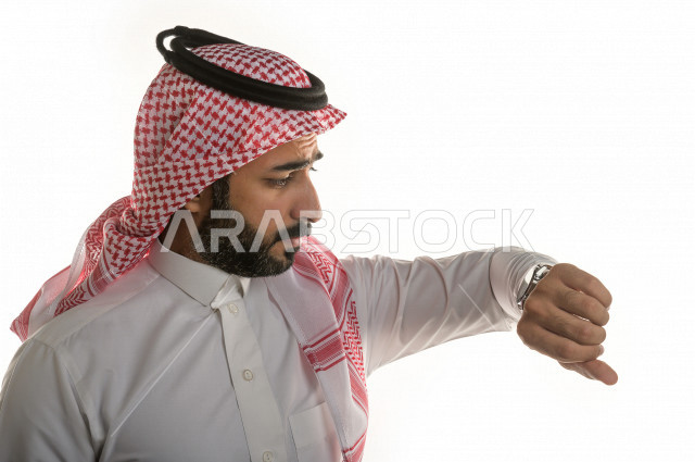 بورتريه لرجل سعودي خليجي  سعيد بإيماءات الوجه المختلفة  ، تعابير وجه و يدين مختلفة  ، يرتدي ساعة يد فاخرة  ، يشير اصبعه الى الساعة ،خلفية بيضاء