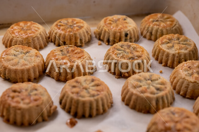 الاستعداد لاستقبال الأعياد والمناسبات الإسلامية السعيدة، قطع معمول العيد الشهية، كرم الضيافة وحسن الاستقبال في السعودية, منتجات محلية وطنية، وضع أقراص المعمول بالعجوة والمكسرات في الصواني، حلى سعودي تقليدي، طريقة إعداد وتحضير الحلويات الشهية