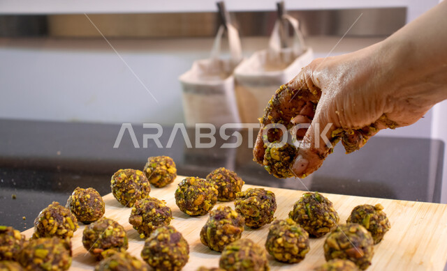 طريقة إعداد وتحضير الحلويات الشهية، الاستعداد لاستقبال الأعياد والمناسبات الإسلامية السعيدة، قطع معمول العيد الشهية، كرم الضيافة وحسن الاستقبال في السعودية, منتجات محلية وطنية، حلى سعودي بالعجوة والمكسرات، صورة مقربة ليد إمرأة تقوم بتشكيل حشوة قرص المعمول