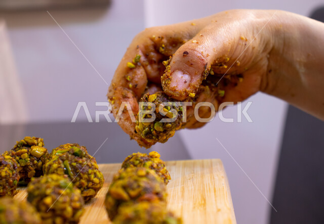 طريقة إعداد وتحضير الحلويات الشهية، الاستعداد لاستقبال الأعياد والمناسبات الإسلامية السعيدة، قطع معمول العيد الشهية، كرم الضيافة وحسن الاستقبال في السعودية, منتجات محلية وطنية، حلى سعودي بالعجوة والمكسرات، صورة مقربة ليد إمرأة تقوم بتشكيل حشوة قرص المعمول