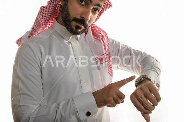 بورتريه لرجل سعودي خليجي  سعيد بإيماءات الوجه المختلفة  ، تعابير وجه و يدين مختلفة  ، يرتدي ساعة يد فاخرة  ، يشير اصبعه الى الساعة ،خلفية بيضاء