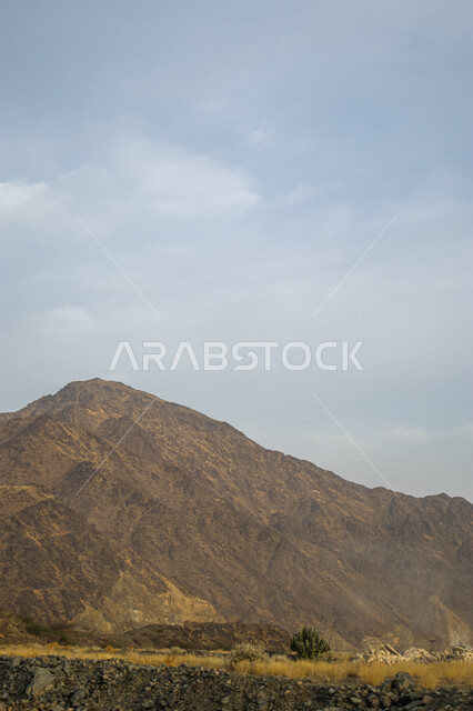 Rocky mountain formations in the desert areas of Saudi Arabia, a mountain range next to a highway during the day, peaks, elevations and terrain in the suburbs