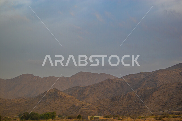 سلسلة جبلية بجانب طريق سفر سريع في النهار، القمم والمرتفعات والتضاريس في الضواحي، التكوينات الصخرية للجبال في المناطق الصحراوية للمملكة العربية السعودية 