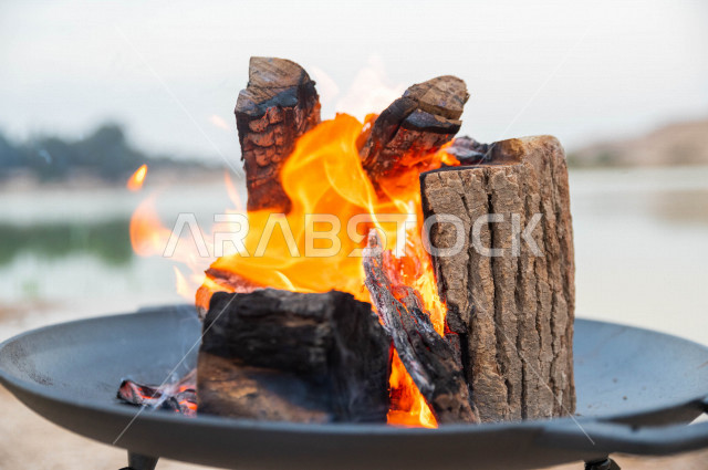 موقد نار مشتعل في احدى الرحلات البرية في صحراء المملكة العربية السعودية في وقت شروق الشمس ، اجواء بريه ممتعة في مناطق صحراوية سياحية ، جمال الطيعية السعودية ، البر و التخييم 