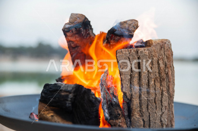 موقد نار مشتعل في احدى الرحلات البرية في صحراء المملكة العربية السعودية في وقت شروق الشمس ، اجواء بريه ممتعة في مناطق صحراوية سياحية ، جمال الطيعية السعودية ، البر و التخييم 