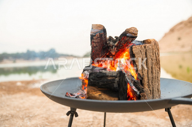 موقد نار مشتعل في احدى الرحلات البرية في صحراء المملكة العربية السعودية في وقت شروق الشمس ، اجواء بريه ممتعة في مناطق صحراوية سياحية ، جمال الطيعية السعودية ، البر و التخييم 