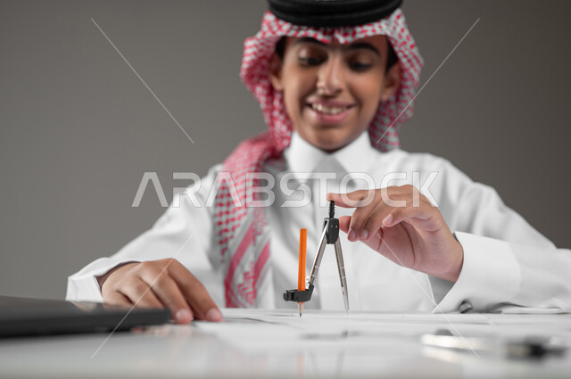 Drawing an engineering design plan, using modern technical devices in scientific fields, gaining knowledge and experience with gestures of precision and focus, a close-up portrait of a Saudi Arabian Gulf boy wearing a shemagh and traditional thobe, sitting at his desk using engineering tools and equipment, gray background, sensitive content, sensitive use