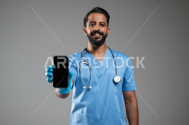Integrating modern technologies into practical life, a close-up portrait of a Saudi Gulf Arab nurse wearing a work uniform and gloves, displaying a blank black screen on a mobile phone, the concept of medicine and health care, Saudi professions and jobs, gray background, sensitive content, sensitive use
