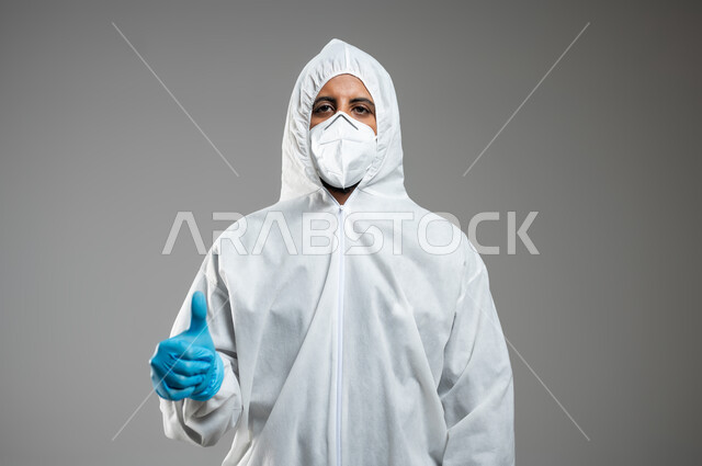 الوقايه خير من العلاج، بورتريه مقرب لممرض عربي خليجي سعودي يرتدي  القناع البلاسيتكي الوقائي والكمامه الطبيه، يشير بأصبع الابهام نحو الاعلى، السيطره على انتشار فايروس كورونا،  اتباع الارشادات لمنع انتقال عدوى الفايروس، خلفيه رماديه، استخدام حساس، محتوى حساس