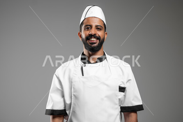 Cooking Saudi food, a close-up portrait of a smiling Saudi Arabian Gulf chef wearing a cooking uniform looking at the camera with confidence and pride, professionalism in the cooking profession, gray background, sensitive content, sensitive use