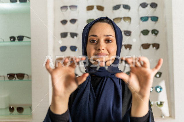 فتاة سعودية تريد تجربة نظارة طبية , لتصحيح قياسات النظر في محل النظارات . 