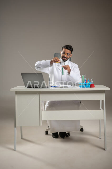 البحث والتطوير وتقدم التكنولوجيا الحيوية، القيام بالدراسات والتفاعلات الكيميائية، استخدام انابيب الاختبار لإجراء التجارب والبحوث العلمية، بورتريه لطبيب مخبري عربي خليجي سعودي يقوم بفحص العينات التحليلية على مكتبه الخاص، خلفيه رماديه، محتوى حساس