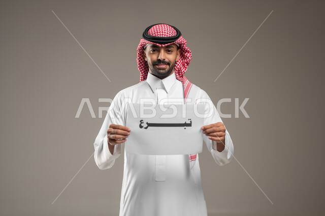 الأعمال الخيرية الإسلاميه، المساعدات والتبرعات الإنسانية، بورتريه مقرب لرجل عربي سعودي خليجي يرتدي الثوب والشماغ السعودي و يمسك بيده ورقه مكتوب بها تبرع، الدال على الخير كفاعله، خلفية رمادية، استخدام حساس، محتوى حساس