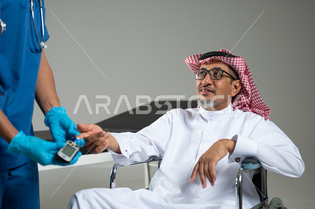 تقديم خدمات الفحص الطبي، استخدام جهاز السكري الالكتروني، بورتريه لممرض يرتدي اليونيفورم يقوم بفحص نسبة السكر لرجل عربي خليجي سعودي يرتدي الثوب التقليدي يجلس على الكرسي المتحرك، الجسم بالطول الكامل، خلفية رمادية، محتوى حساس، استخدام حساس