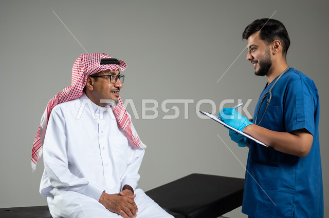 تقديم الخدمات الطبية، بورتريه مقرب لممرض عربي خليجي سعودي يرتدي اليونيفورم يقوم بتدوين المعلومات العامة لمريض مسن يرتدي الثوب التقليدي والشماغ يجلس على سرير المرضى، خلفية رمادية، محتوى حساس ، استخدام حساس