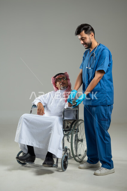 مراجعة وفحص عام لدى الطبيب، مفهوم الطب و الرعاية الصحية، بورتريه لممرض عربي سعودي خليجي يرتدي اليونيفورم والقفازات يقيس سكر الدم لمريض كبير بالسن يرتدي الثوب التقليدي والشماغ ، الجسم بالطول الكامل، خلفية رمادية، محتوى حساس، استخدام حساس .
