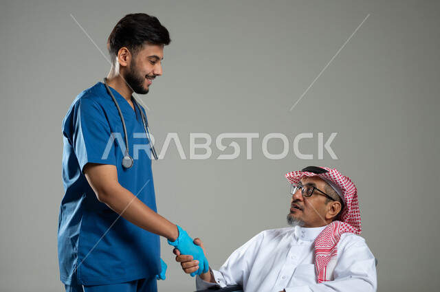 الاهتمام والاعتناء بمرضى ذوي الهمم، تقديم الخدمات والاحتياجات الخاصة بكل كفاءة، مفهوم الطب والرعاية الصحية، بورتريه مقرب لممرض يرتدي اليونيفورم يقوم بمصافحة رجل عربي خليجي سعودي مقعد يرتدي الثوب التقليدي، خلفية رمادية ، محتوى حساس، استخدام حساس .