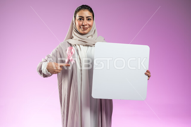 The logo of the global campaign to challenge malignant diseases, billboards for breast cancer awareness and education, a close-up portrait of a smiling, veiled Saudi Arabian Gulf woman wearing an abaya pointing with her index finger at an empty white mockup, an empty white billboard, pink background, sensitive content, sensitive use