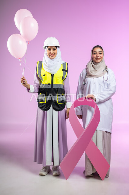 شعار الحملة العالمية لتحدي سرطان الثدي, بورتريه لطبيبه عربيه خليجيه سعوديه ترتدي المعطف الابيض  تحمل شعار التوعيه بالكشف المبكر للأمراض الخبيثه تقف مع مهندسة ترتدي العباءه مع خوذه وستره الحمايه، الجسم بالطول الكامل، خلفية ورديه، محتوى حساس، استخدام حساس