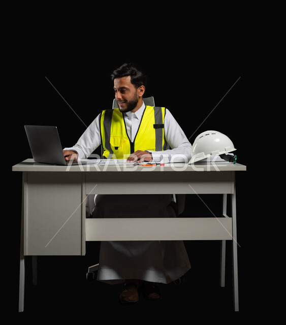 استخدام الأجهزة التقينة الحديثة في المجال الهندسي, دراسة أساسيات المشروع, بورتريه  لمهندس عربي خليجي سعودي  يرتدي الثوب التقليدي و السترة الخاصة بالعمل يجلس على المكتب وأمامه مخططات هندسية معمارية, خلفية سوداء، الجسم بالطول الكامل، استخدام حساس، محتوى حساس