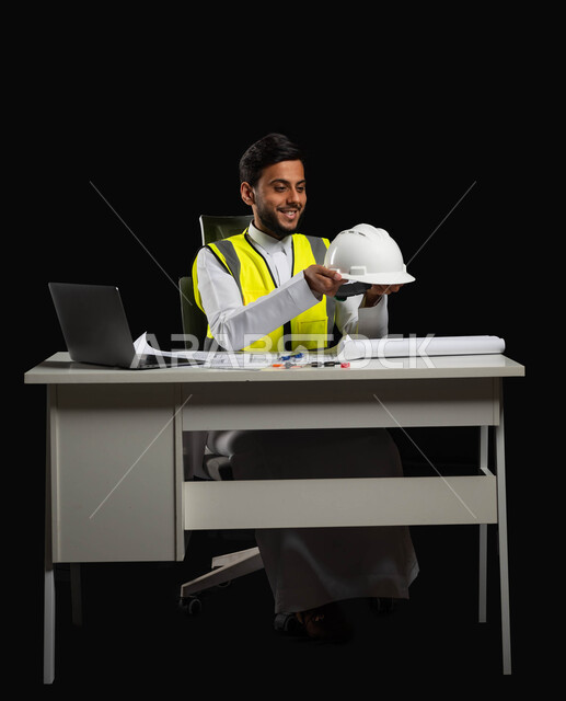 تطوير وتنمية المجال الهندسي السعودي، النظر الى خوذه الحمايه البيضاء بايماءات السرور والفخر، بورتريه مقرب لرجل عربي خليجي سعودي يرتدي الثوب التقليدي مع السترة الخاصة بالعمل، مهن ووظائف سعودية, خلفية سوداء، الجسم بالطول الكامل، محتوى حساس, استخدام حساس