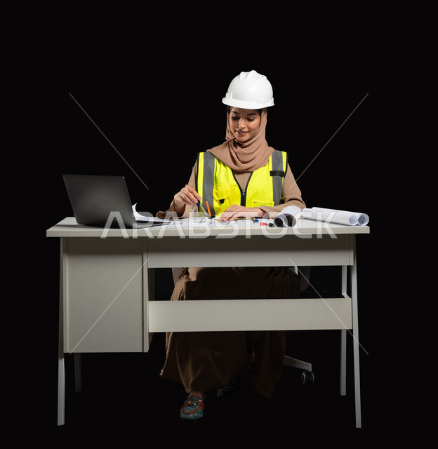 الإعمار بسواعد أبناء الوطن، إدارة الأعمال والمخططات الهندسية، بورتريه لمهندسة عربية خليجية سعودية محجبة ترتدي خوذة الحماية والسترة الخاصة بالعمل تجلس على المكتب وترسم المخطوطات المعمارية, مشروع بناء, متابعة استراتيجات المشروع, خلفية سوداء